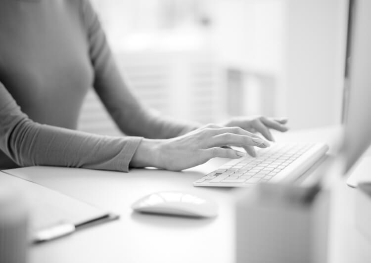 Une jeune femme rédige un contrat d’assurance IDCWIN sur son ordinateur